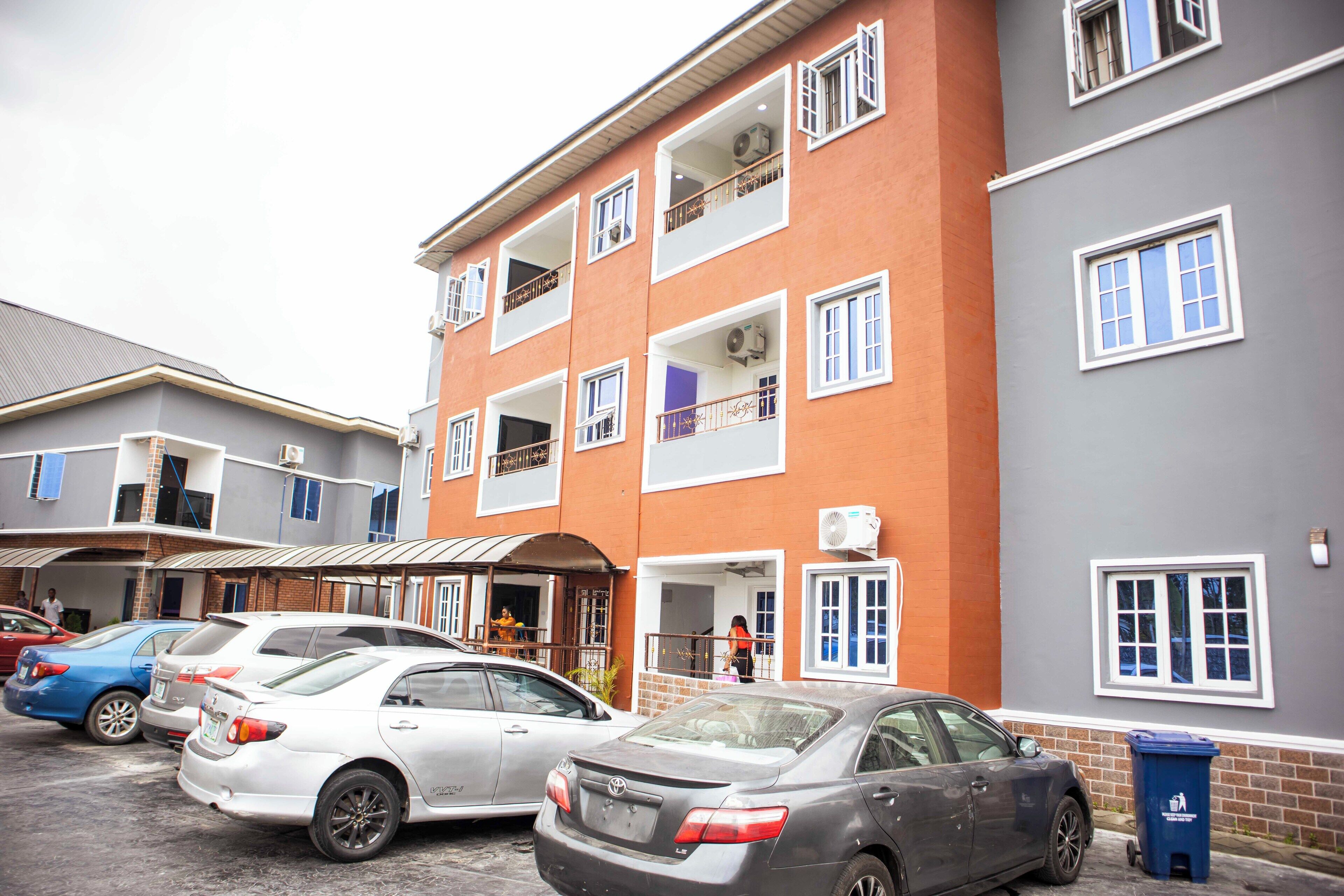 A multi-story building with several cars parked in front.