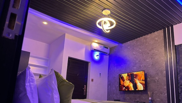 Quarto de hotel moderno com cama, televisão e luminária no teto.