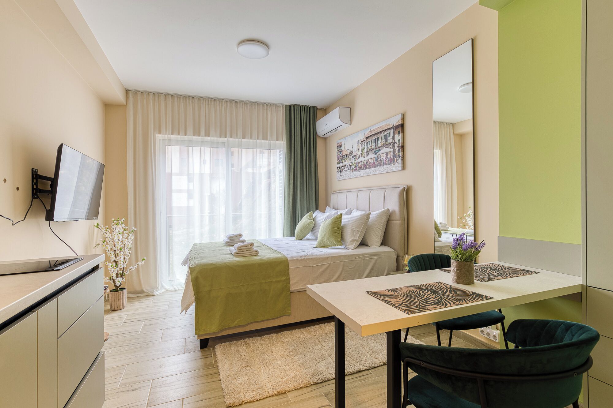 Une chambre d’hôtel avec un lit, un bureau, une chaise, une télévision et une fenêtre avec des rideaux.