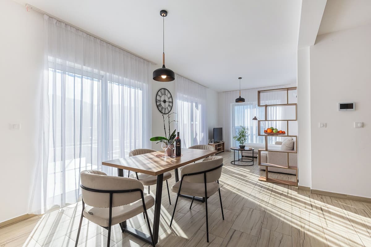 Ein modernes Wohnzimmer mit Essbereich, großen Fenstern und minimalistischem Design.