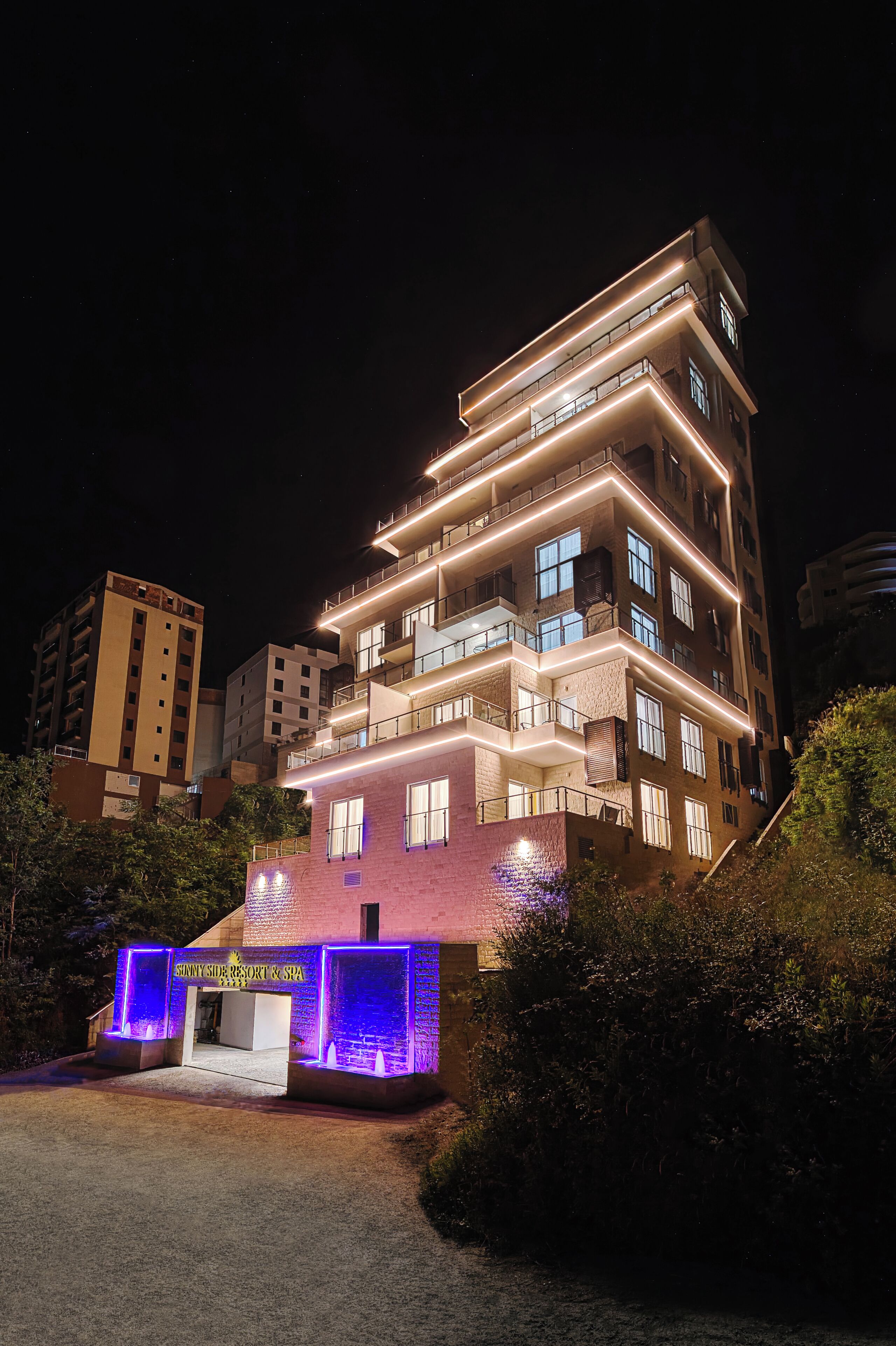 A multi-story hotel with a prominent entrance, balconies, and a well-lit facade.