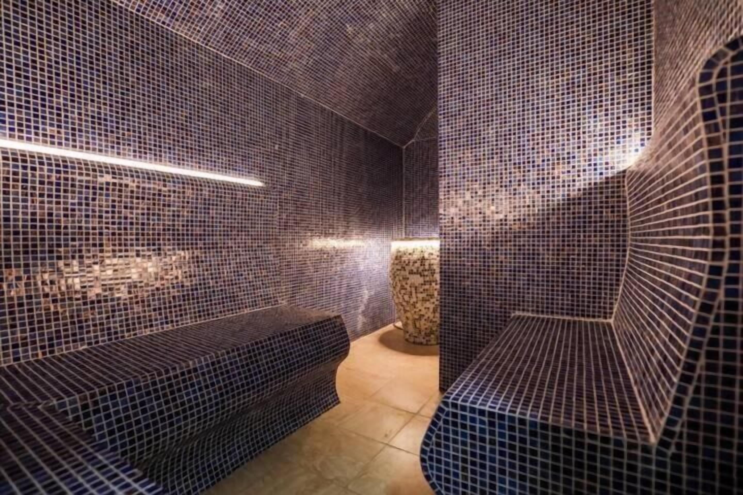 Um espaço com azulejos, bancos e piso em azulejo.