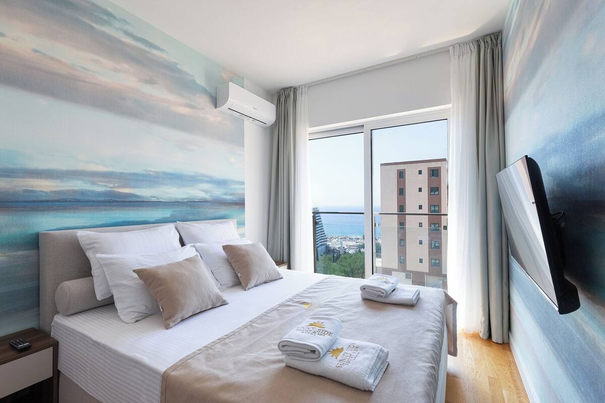 Ein Hotelzimmer mit Bett, Fernseher, einem Gemälde und Blick auf die Stadt.