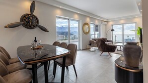 Una sala de estar moderna con comedor, ventanas amplias y un reloj decorativo.
