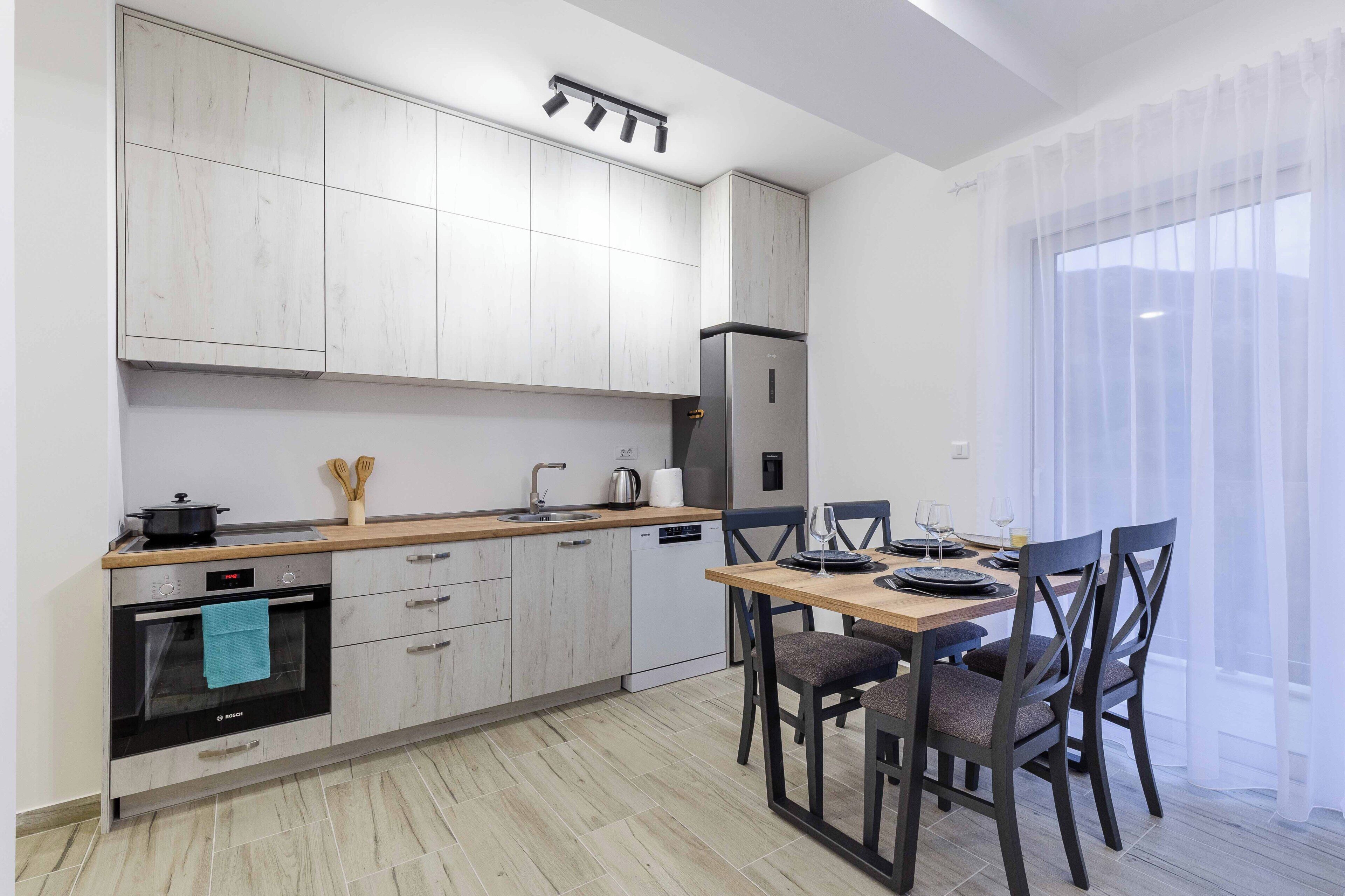 Una cocina moderna con horno empotrado, un refrigerador y un comedor con mesa y sillas.