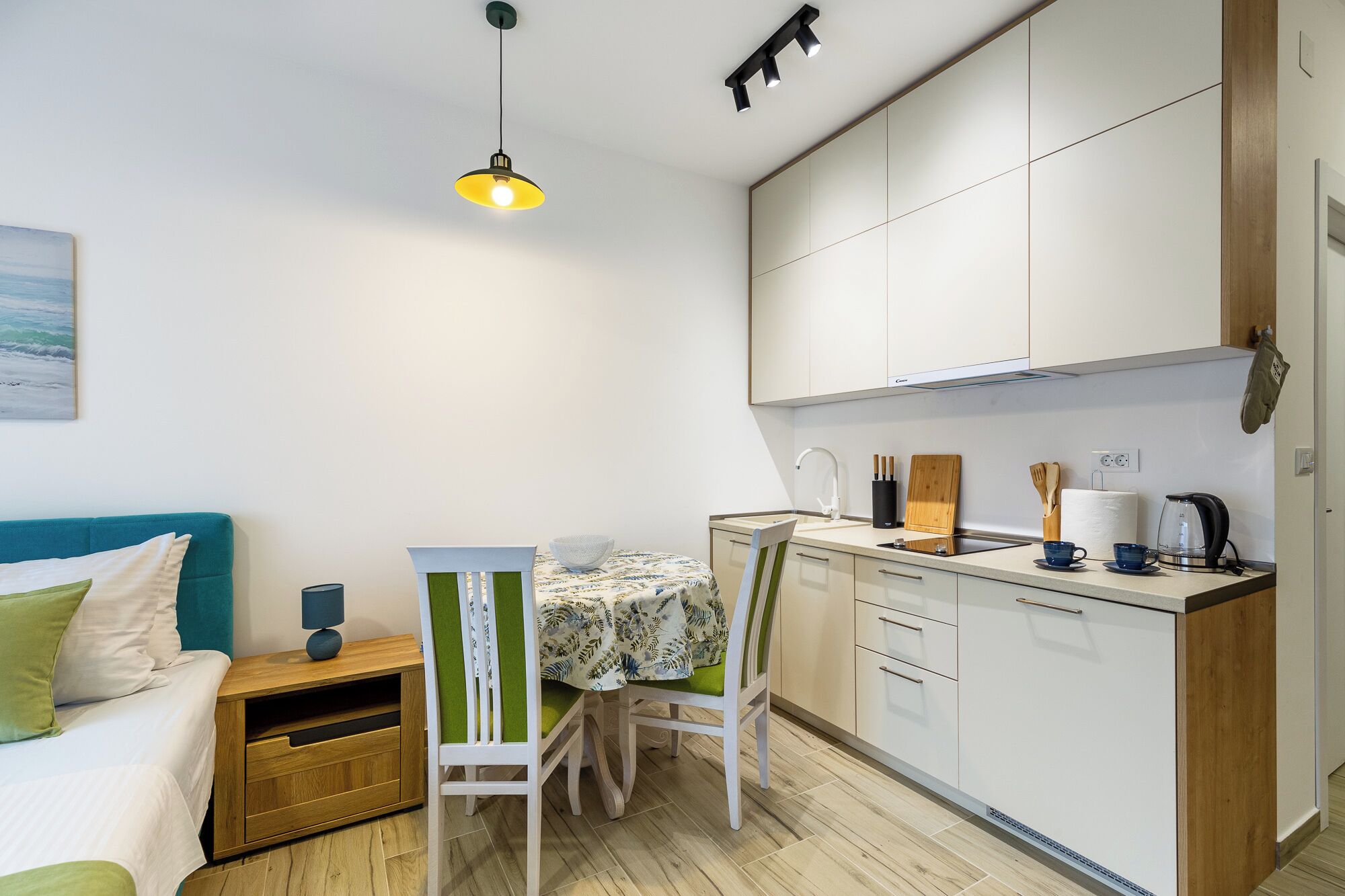 Una cocina compacta con armarios blancos, una encimera de madera y una pequeña mesa de comedor con sillas.