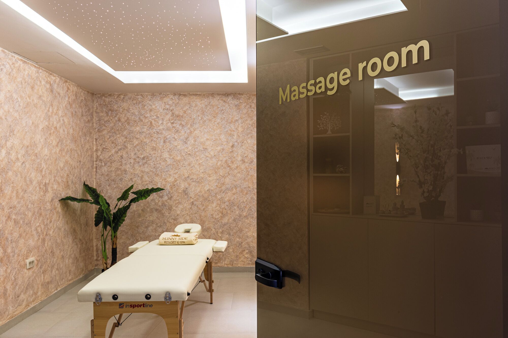 A massage room with a reception area, a reception desk, and a massage table.