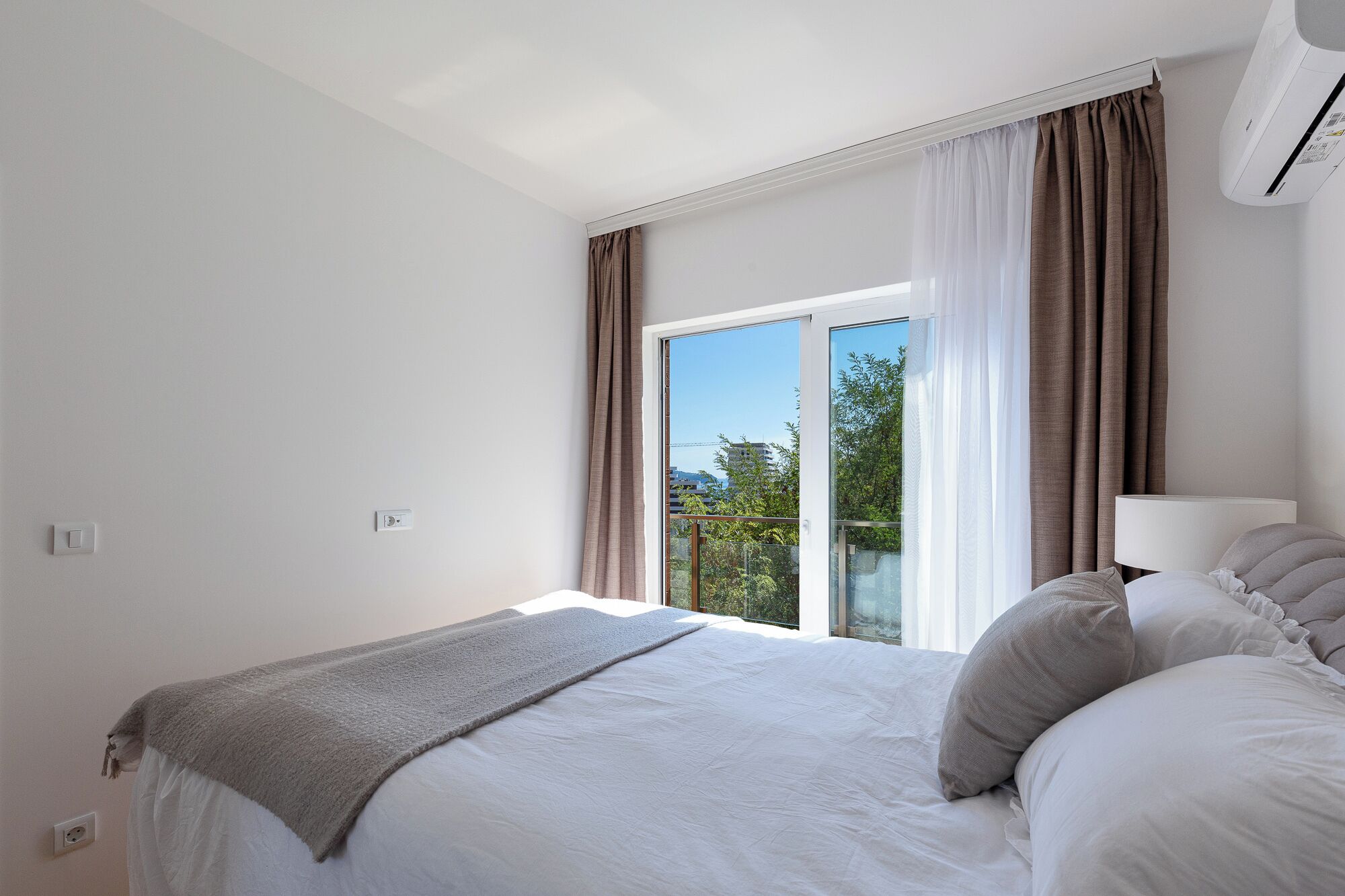 Una camera da letto con un letto, una finestra con tende e un condizionatore.