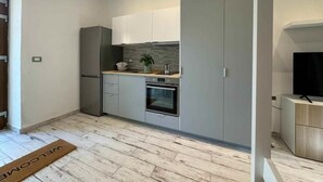 Eine moderne Küche mit grauen Schränken, einem eingebauten Backofen und einem Edelstahl-Kühlschrank.