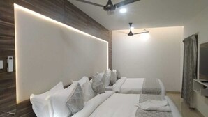 A modern hotel room with two beds, a ceiling fan, and a large mirror. - HOTEL ADHIKRISHNA ARCADE (Erode)