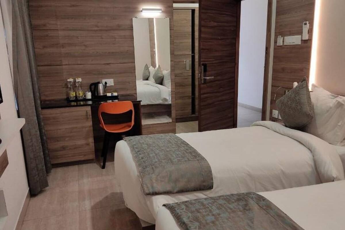 Habitación de hotel con cama, escritorio, silla, espejo y armario.