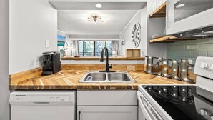 A modern kitchen with a wooden countertop, stainless steel sink, and a built-in oven.
