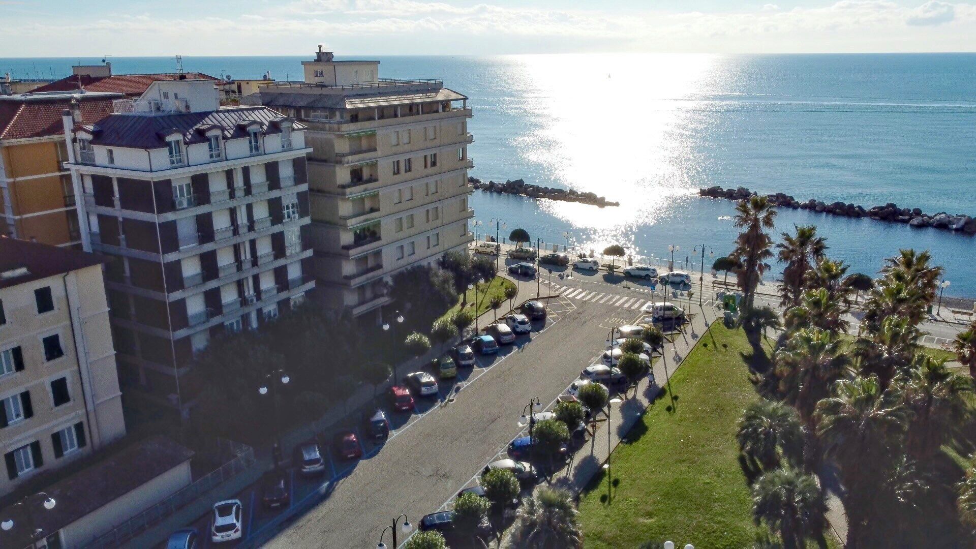 A coastal urban area with a parking lot, buildings, and a view of the sea.