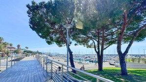 Une promenade en bois dotée de rampes métalliques, qui mène à une marina où sont amarrés des bateaux.