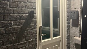 A white-framed door with a glass panel, a black wall with a brick pattern, and a black door with a white handle. - Sheffield Spacious 4 Bedroom House-all En-suites (Sheffield)