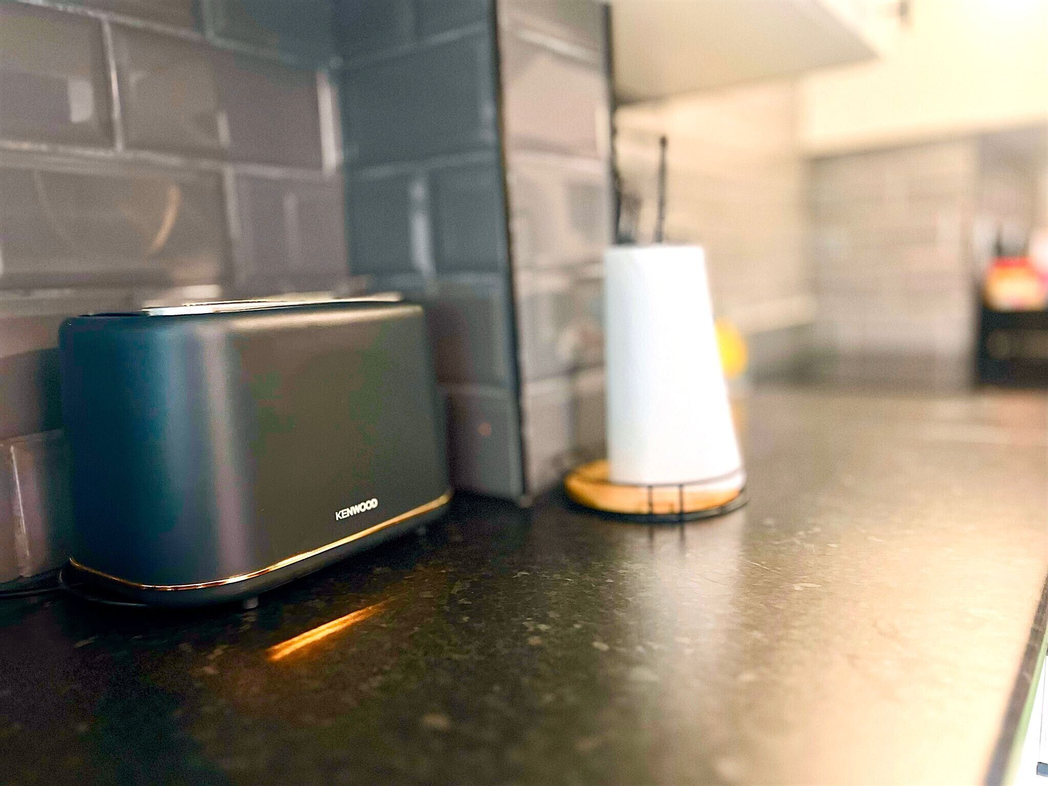 A kitchen counter with a blue portable speaker and a white charging device.