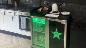 A kitchen with a refrigerator displaying a green neon star logo, a kettle, and various food items on the counter. - Sheffield Spacious 4 Bedroom House-all En-suites (Sheffield)