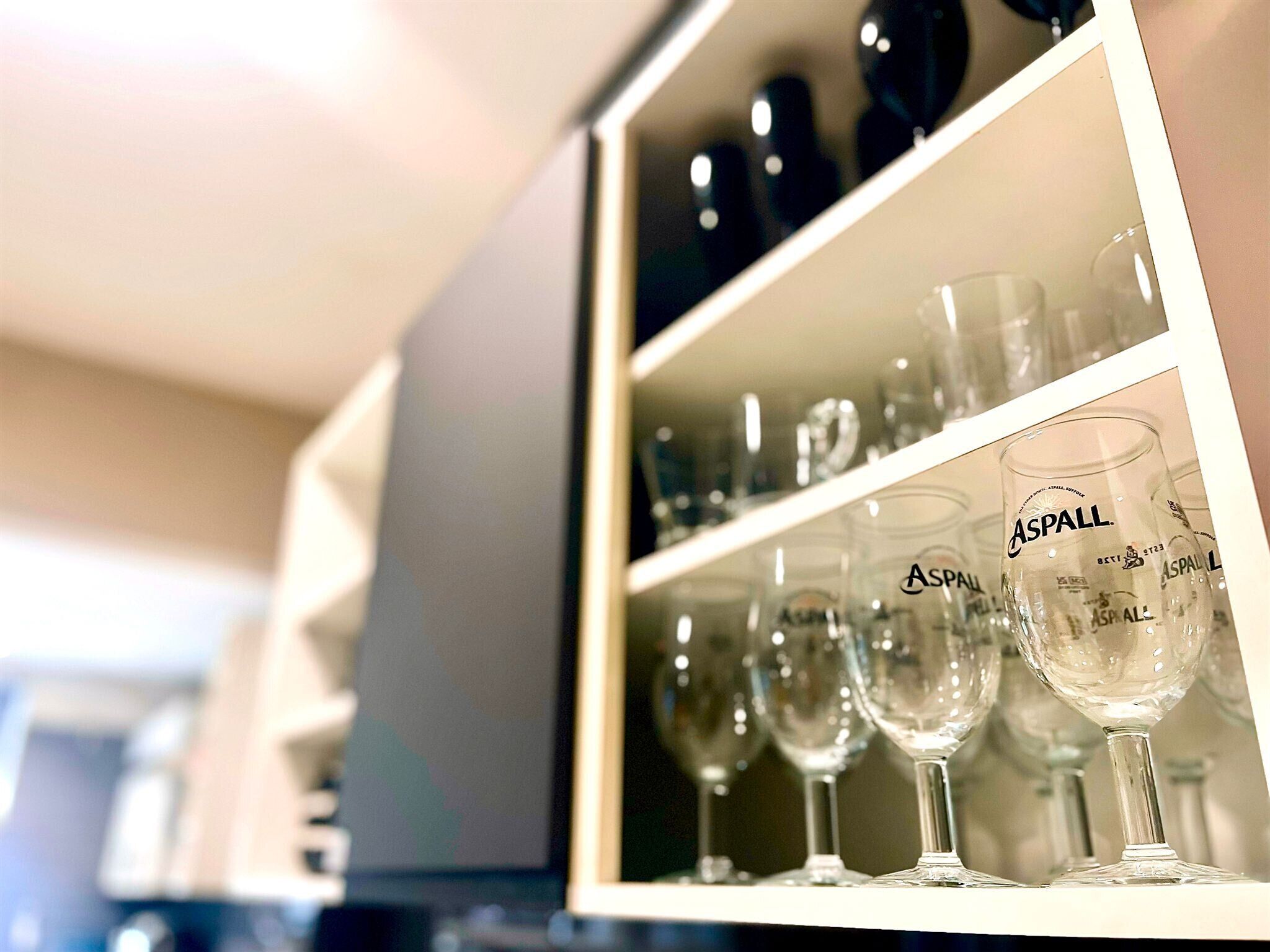 Exhibición de cristalería transparente con la marca 'ASPALL' en las estanterías.