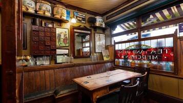 Un interior de restaurante acogedor con bancos de madera, una mesa de madera y un ventanal de vidrio emplomado.