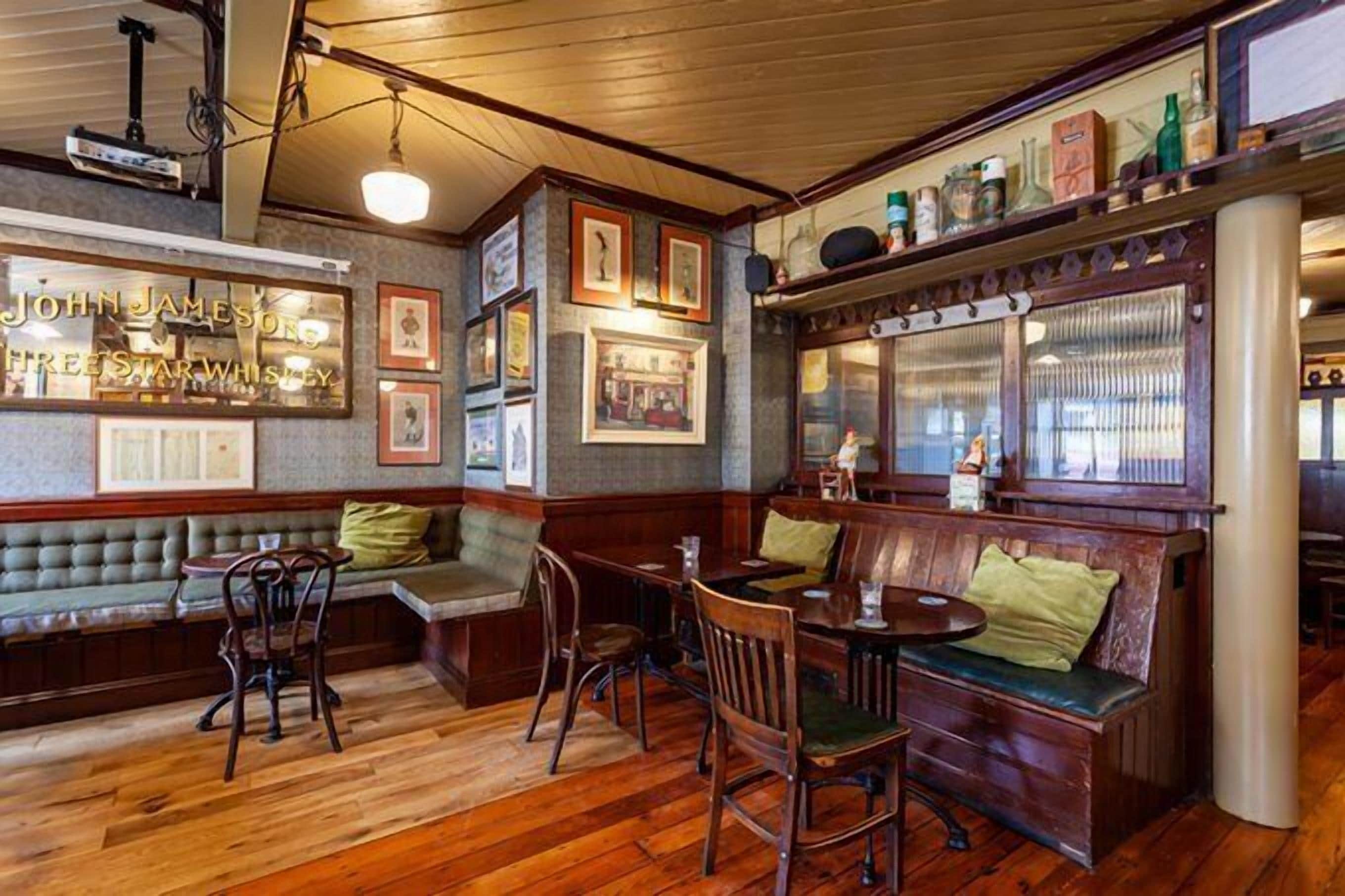 A cozy interior with wooden furniture, a bar area, and framed pictures on the walls.