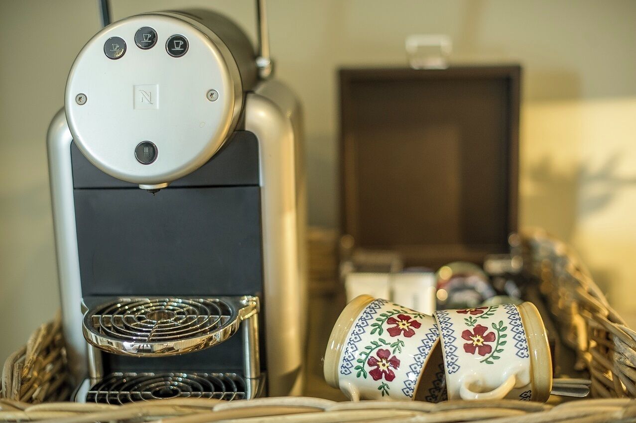 A coffee machine with a control panel and a basket of coffee cups.