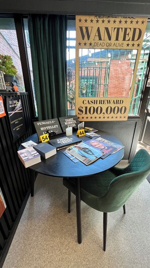 A table with books, a cash reward sign, and a wanted poster. - Fengselshotellet (Arendal)