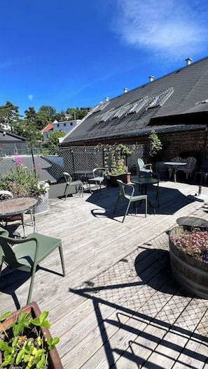 A rooftop patio with outdoor furniture, a pergola, and a view of the surrounding neighborhood. - Fengselshotellet (Arendal)