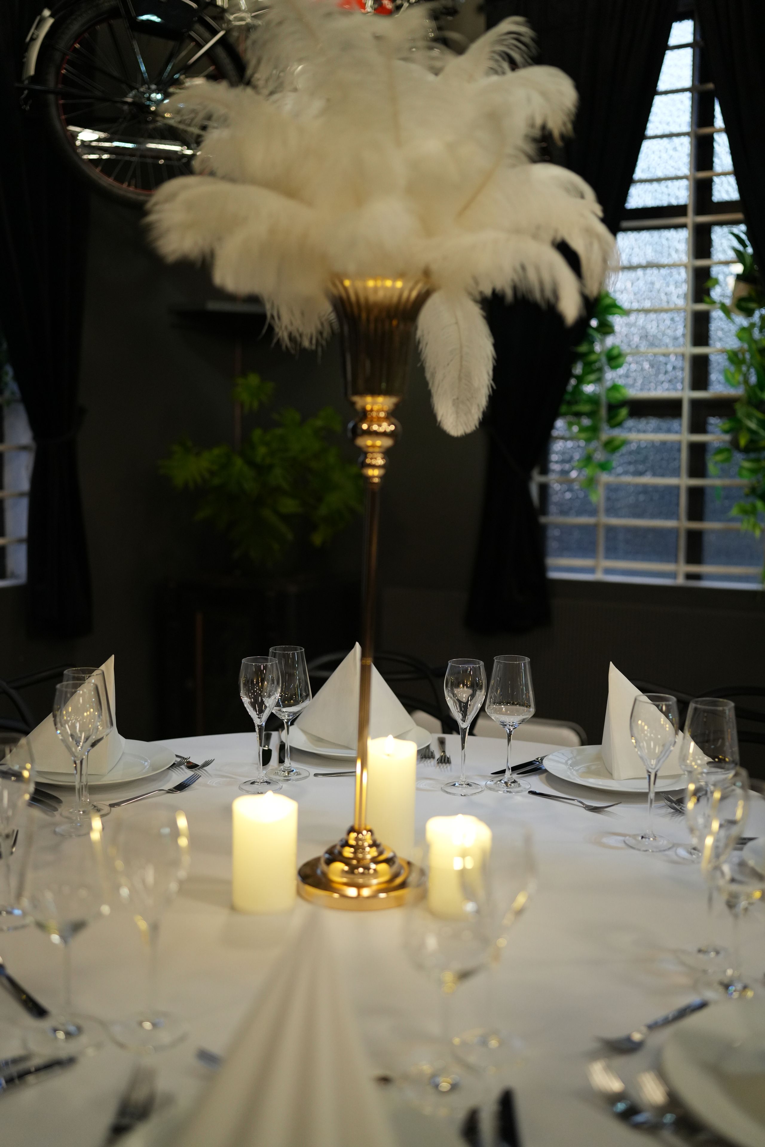 Een gedekte tafel voor een diner, met kaarsen, glazen en een decoratief middelpunt.