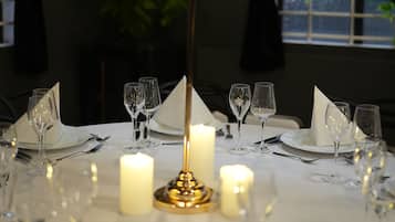 Een gedekte tafel voor een diner, met kaarsen, glazen en een decoratief middelpunt.