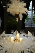 Mesa lista para cenar con velas, copas y un centro de mesa decorativo.