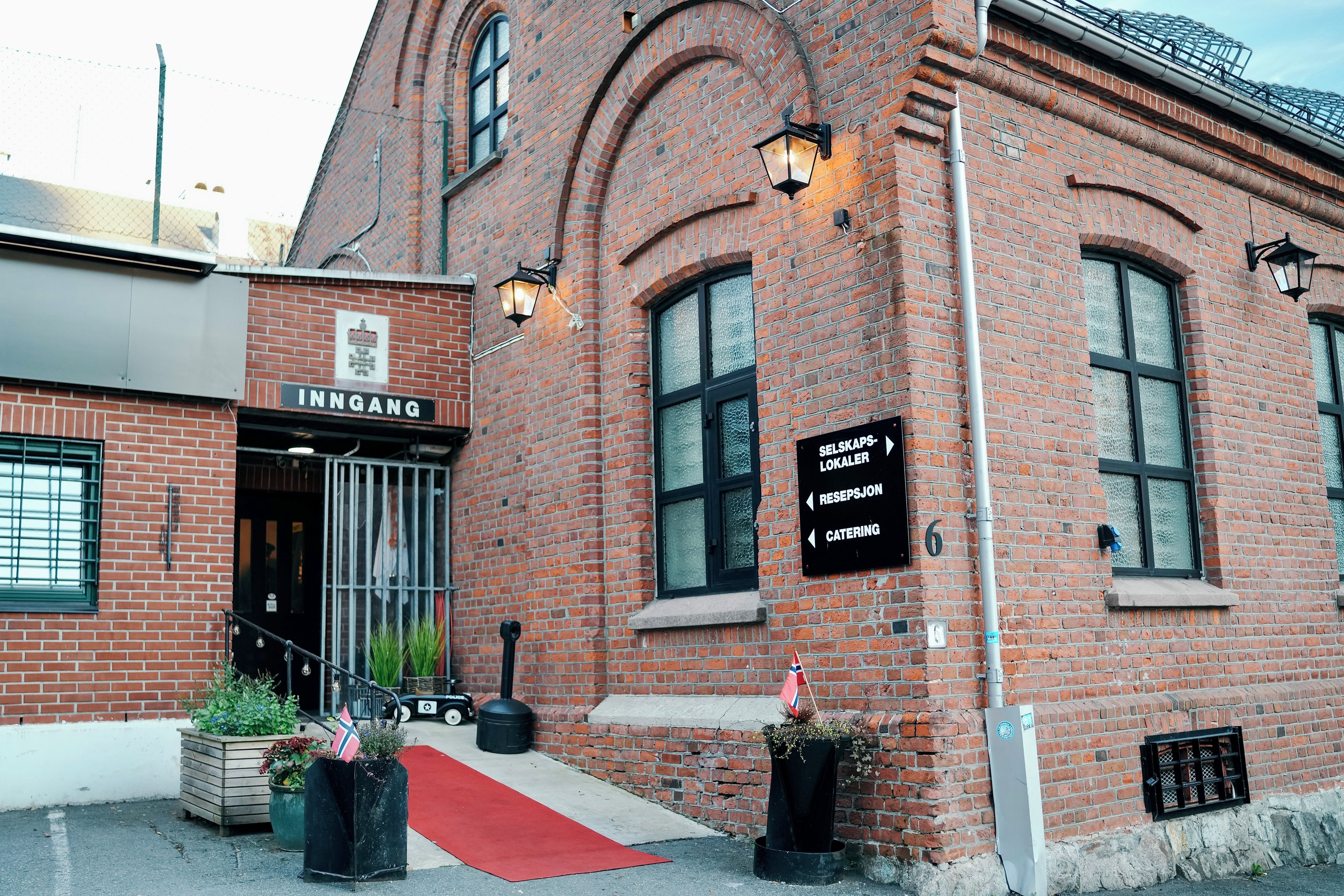 Un bâtiment en briques avec une enseigne indiquant « ENTRÉE » et une autre indiquant les services de « RÉCEPTION » et de « RESTAURATION ».