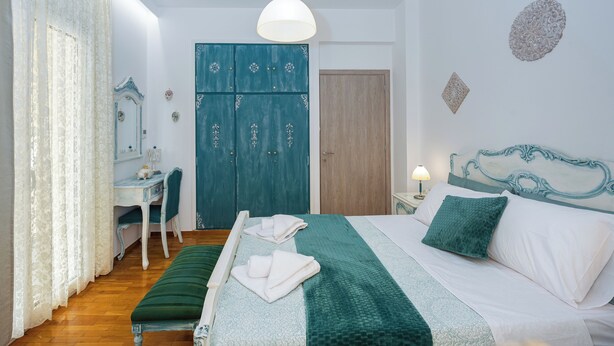 A bedroom with a bed, a desk, a chair, a wardrobe, and a mirror.