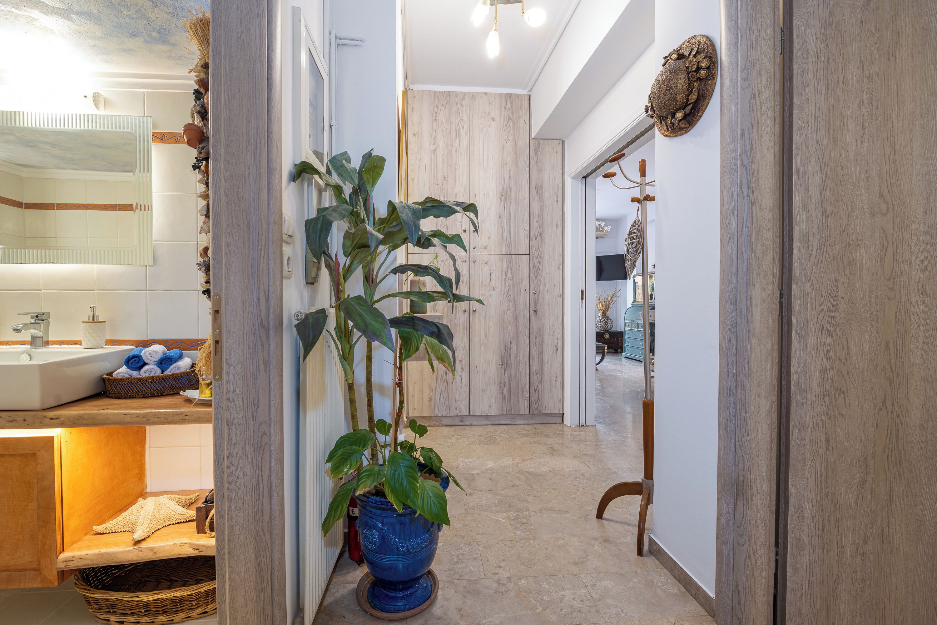 A modern bathroom with a sink, towel rack, and a large potted plant.