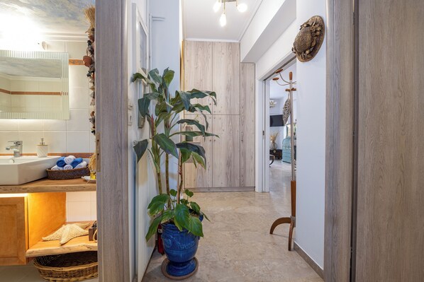 A modern bathroom with a sink, towel rack, and a large potted plant.