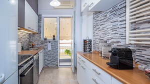 A modern kitchen with white cabinets, a wooden countertop, and a tiled backsplash.