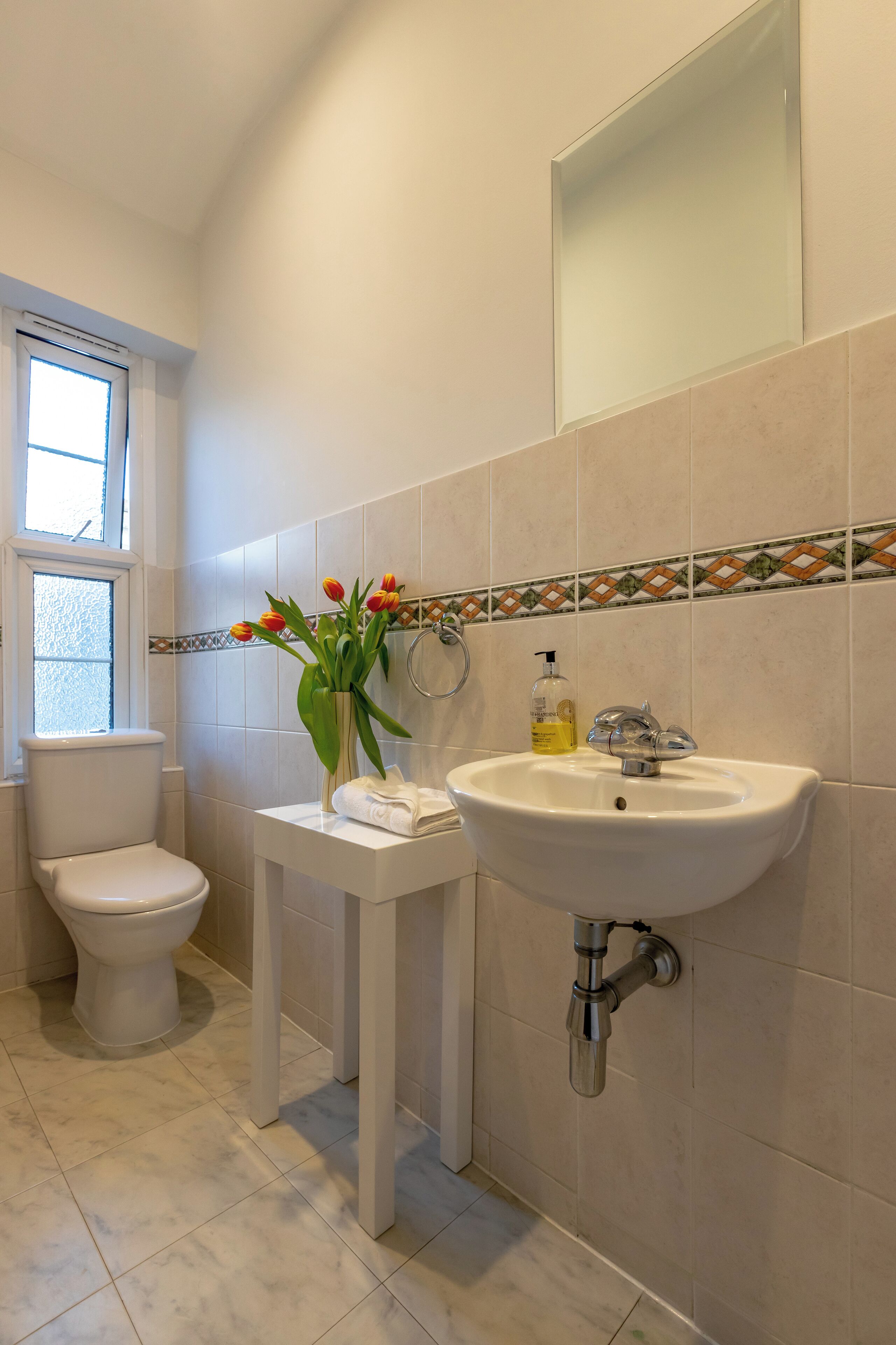Une salle de bain avec des toilettes, un lavabo et une fenêtre.