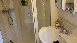 A bathroom with a glass-enclosed shower, a white sink with a single faucet, and a mirror above the sink. - Immaculate 3-bed Caravan 10mins From Gt Yarmouth (Great Yarmouth)