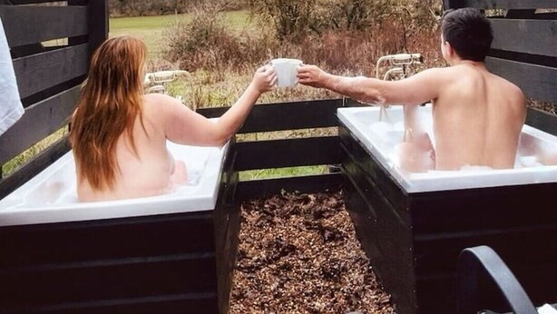 Two people in a hot tub with a view of a garden and trees. - Extremely remote elegant hut set with valley views immersed in nature.  (Sittingbourne)