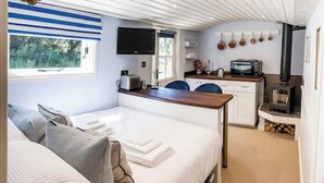 A compact, well-lit room with a bed, a small kitchenette, a window, and a ceiling with linear patterns. - Extremely remote elegant hut set with valley views immersed in nature.  (Sittingbourne)
