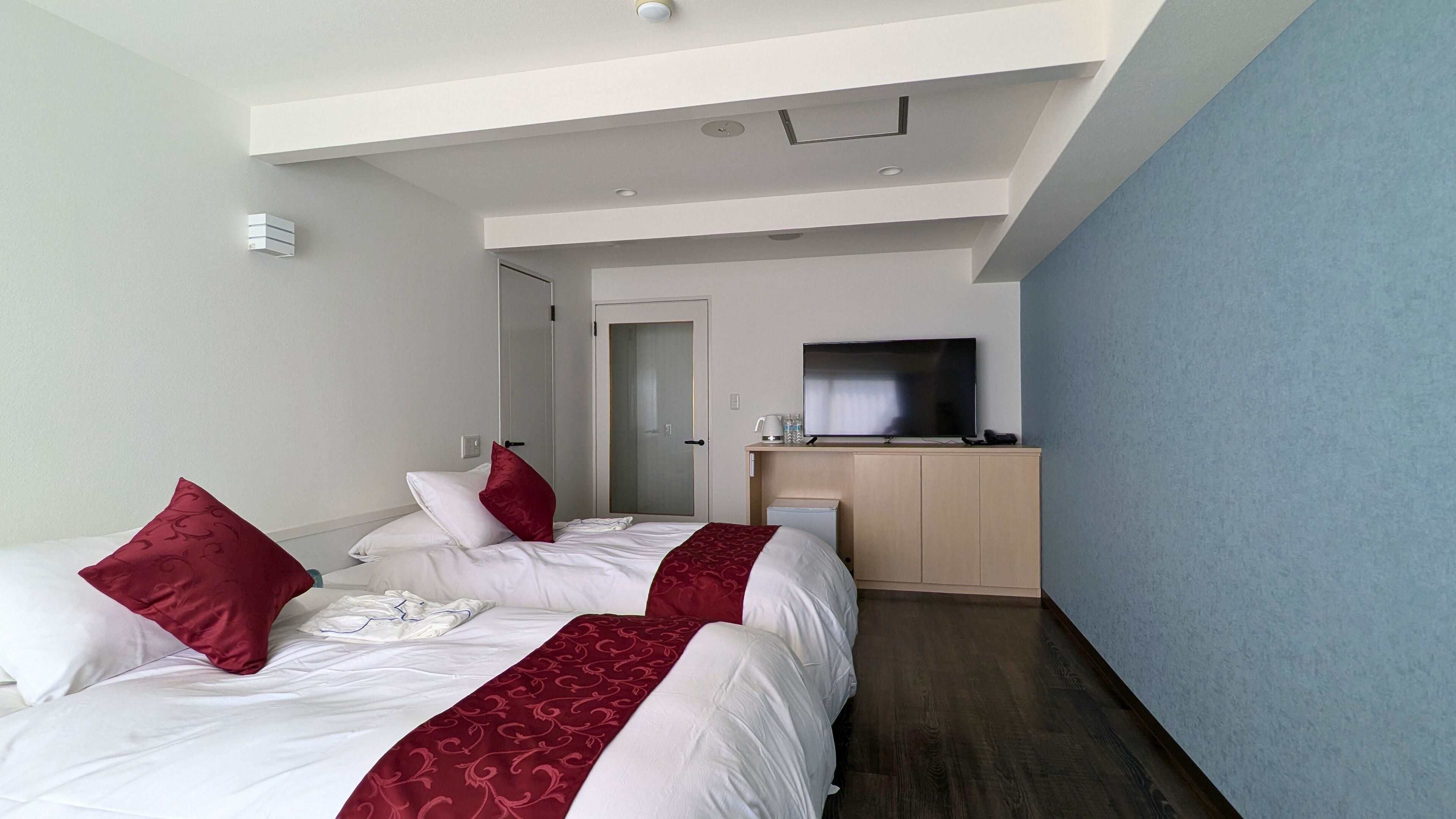 Una habitación de hotel con dos camas, televisión y un minibar.
