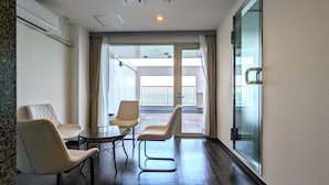 Une chambre d’hôtel avec une porte vitrée donnant sur un balcon, deux chaises et une petite table.