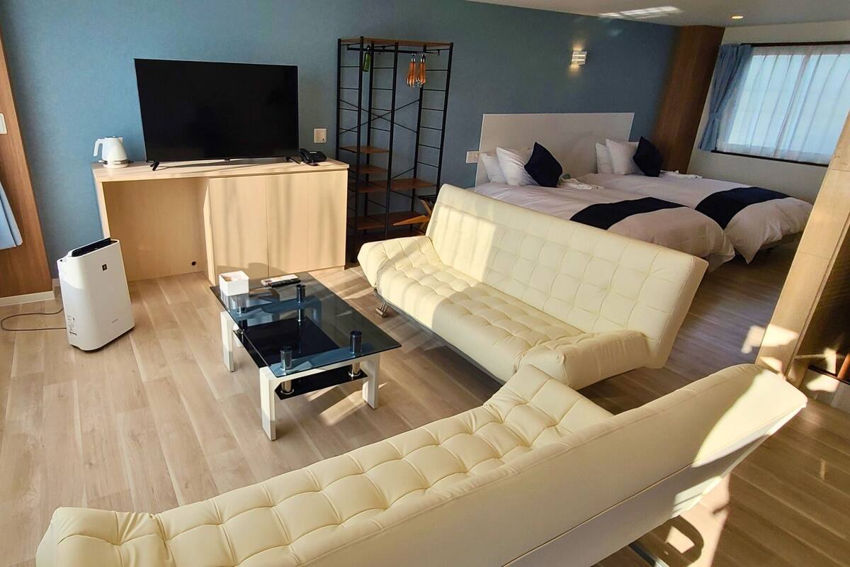 Une chambre d’hôtel moderne équipée d’un grand lit, d’un canapé, d’une télévision et d’un bureau.