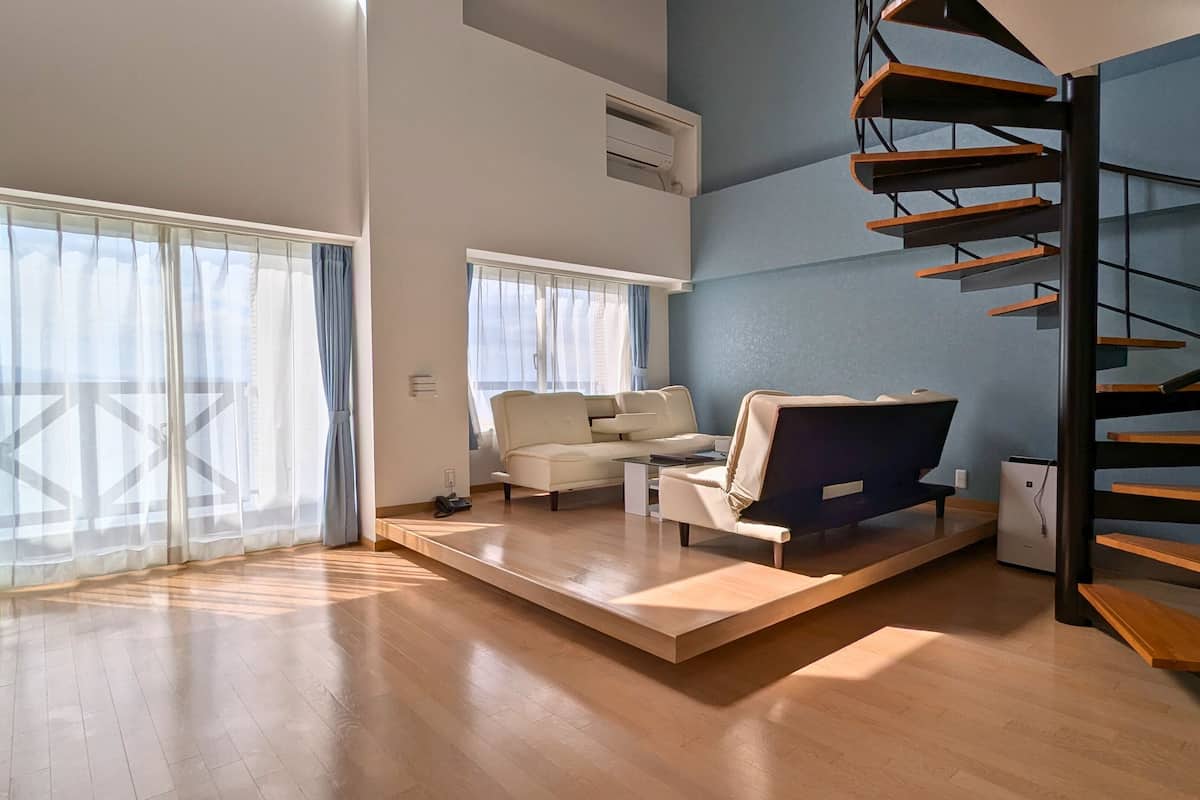 Un salon spacieux avec un escalier moderne, un canapé et une table basse.