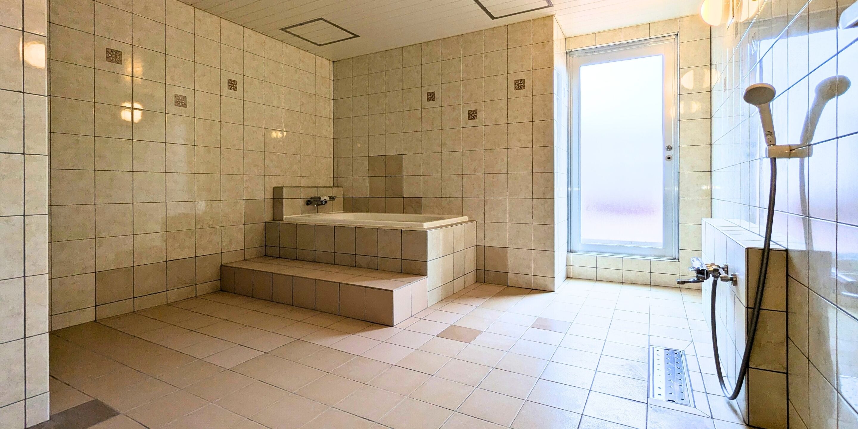 Un baño moderno con bañera, zona de ducha y ventana que proporciona luz natural.