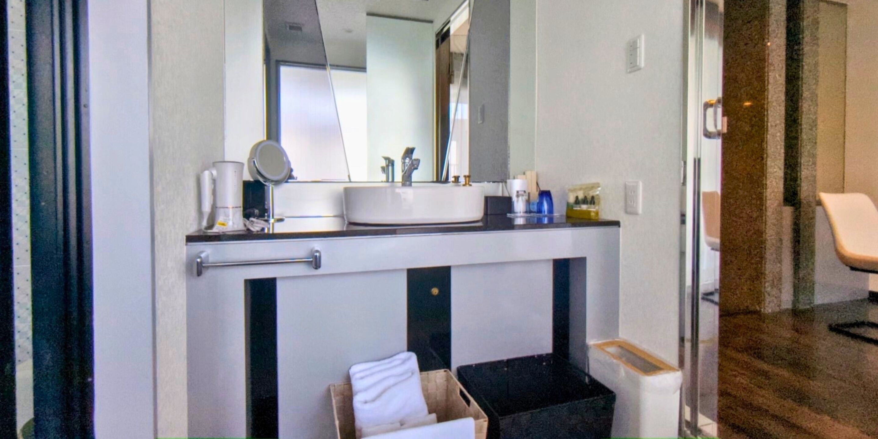 A bathroom with a sink, mirror, and towel storage.