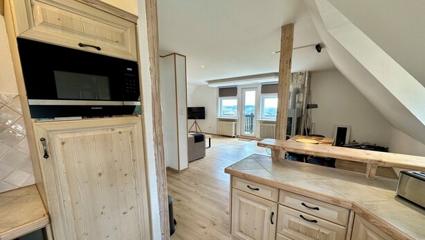 A modern kitchen with wooden cabinets, a built-in microwave, and a large window overlooking a scenic view. - 100 m² in Bester Fernblicklage im Haus Schneekappe (Winterberg)