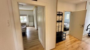A room with a bed, a wardrobe, a black metal shelf unit, and a door leading to another room. - 100 m² in Bester Fernblicklage im Haus Schneekappe (Winterberg)