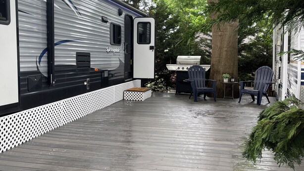 A covered deck area with a grill and outdoor seating. - Nature's Haven Tiny Home (Bear)