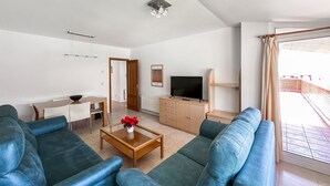 En moderne stue med en sofa, et sofabord med blomster, et fjernsyn og et spiseområde.