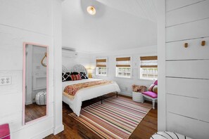 Un dormitorio con cama, una silla, un ventanal y un espejo.